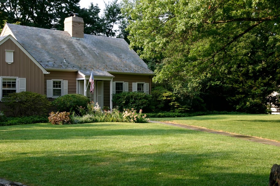 A green lawn and a small brown house. 