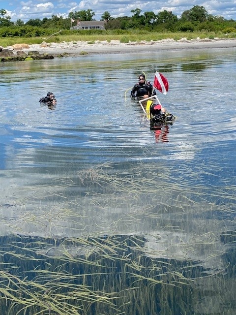 Photo of three EPA scientists, left to right, Cayla Sullivan, Evelyn Spencer, and Jean Brochi (with flag), helping to establish a seagrass monitoring site off Fishers Island in August 2023. Photo by Katie Lund, CT NERR.