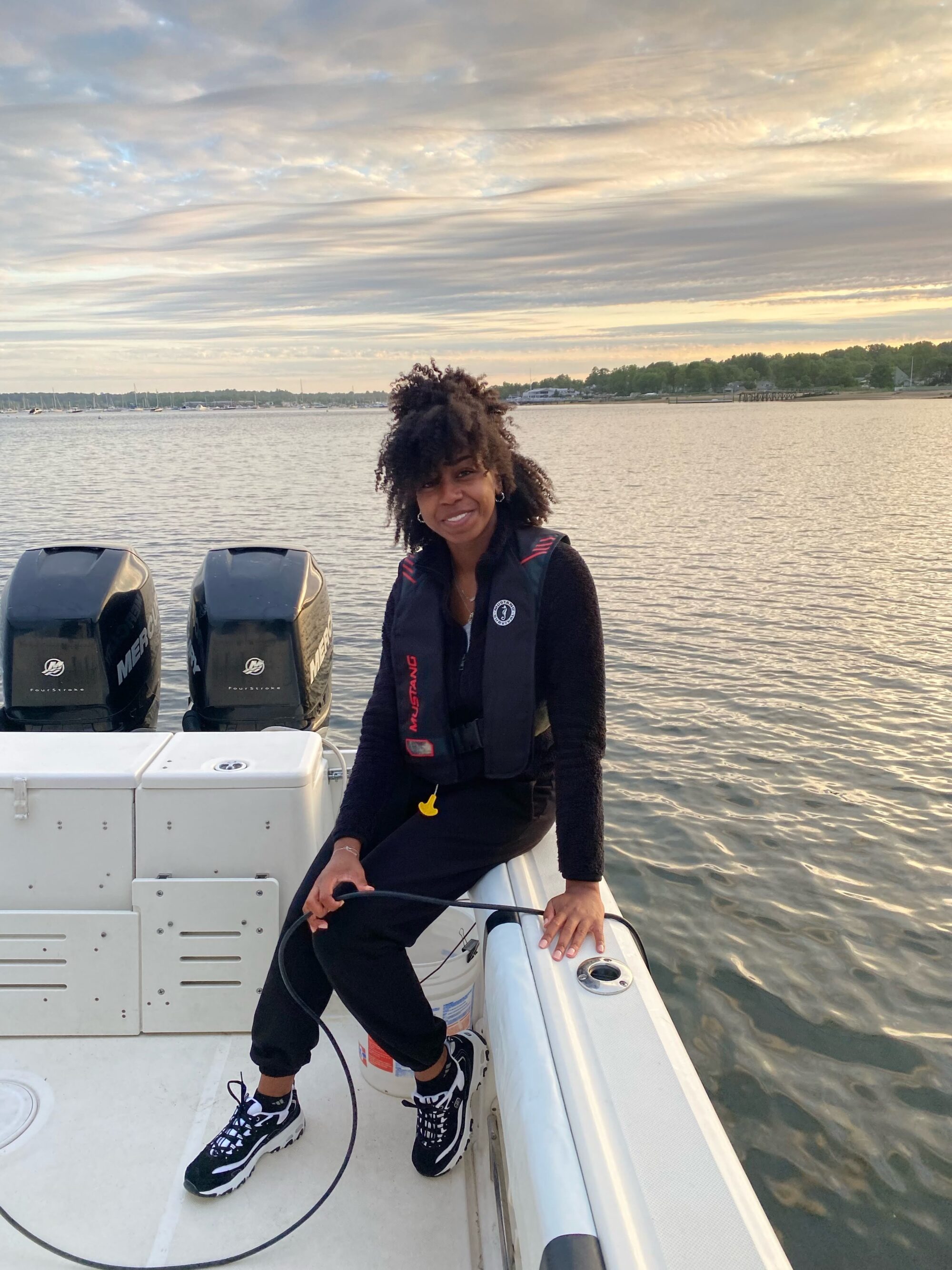 Samantha Wilder sits on the edge of a boat out on the water. 