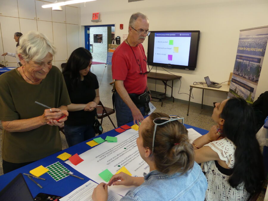 Participants write their comments and recommendations for the Revised Comprehensive and Conservation Management Plan at the Sustainable and Resilient Communities Table. The display table is located in a meeting room at the Alley Pond Environmental Center in Queens, where a public engagement session for the CCMP revision was being held.