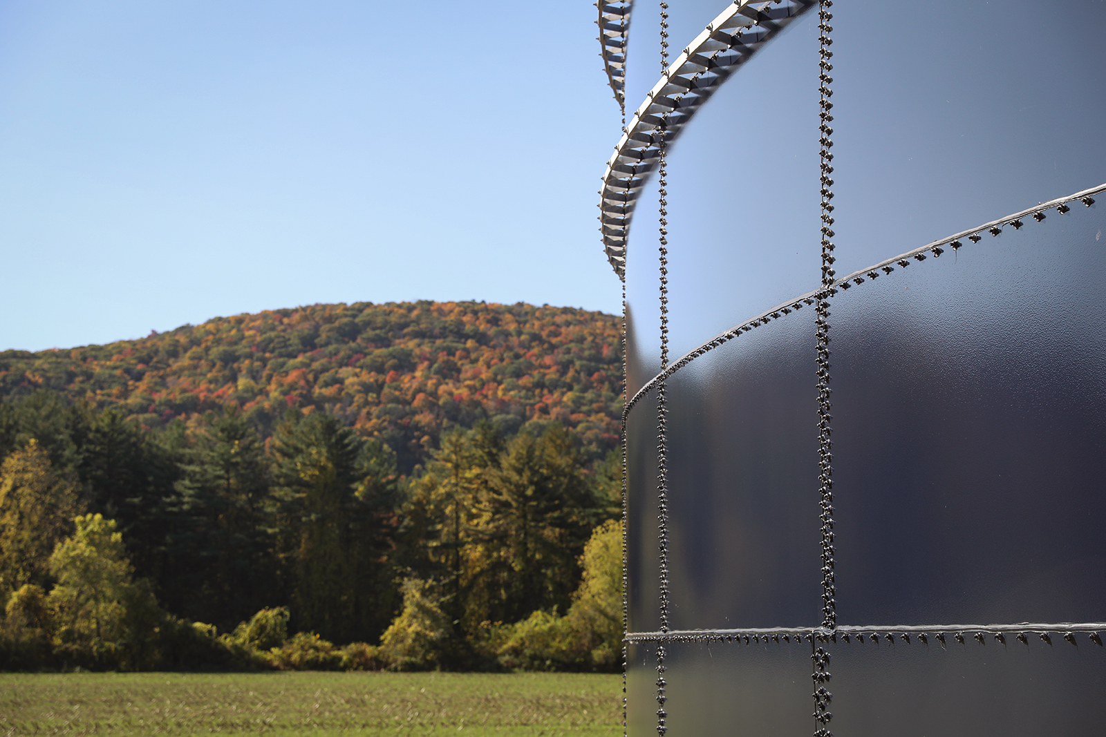A black shiny manure storage structure with foliage.