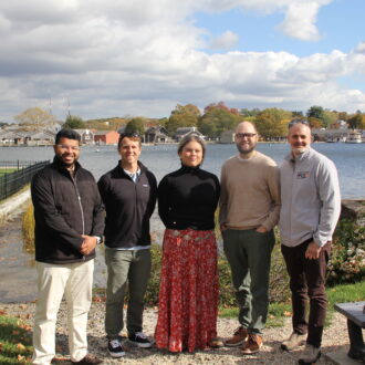 Municipal officials leading the resilience project in the Mystic section of Groton are, left to right, Sabit Nasir, sustainability and resilience manager; Johathan Reiner, director of planning and development services; Alexis Torres, sustainability and resilience specialist; Geoff Foster, town engineer; and Dave Prescott, planner II/floodplain manager. They are standing at a public access area in a neighborhood that borders the Mystic and is susceptible to flooding.